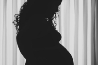 Pregnant woman looks down at her stomach