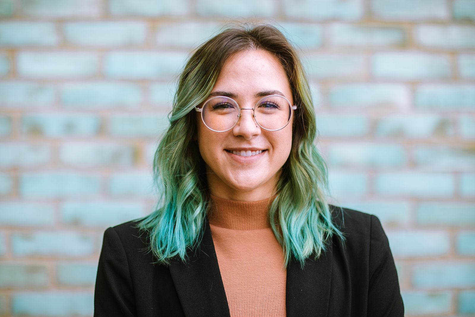 Dr. Olivia Aspiras standing in front of teal green brick wall