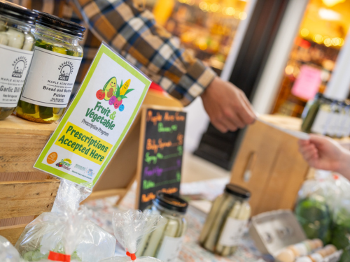 Child gives Fruit and Vegetable Prescription paper to worker at farmer's market