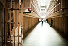 Inside of a jail corridor with a few people standing in the distance