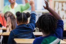 Students in class raising hands
