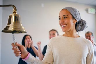 Woman with cancer ringing chemotherapy bell