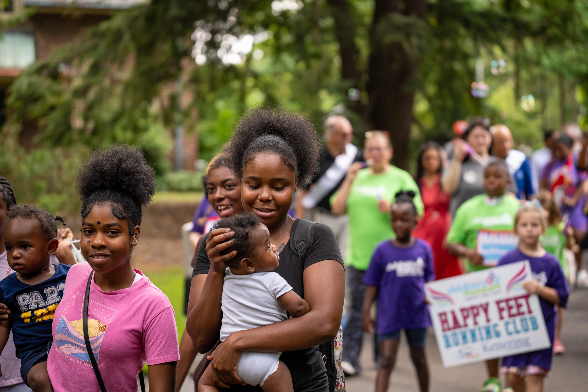 Moms and children smiling and participating in a baby parade